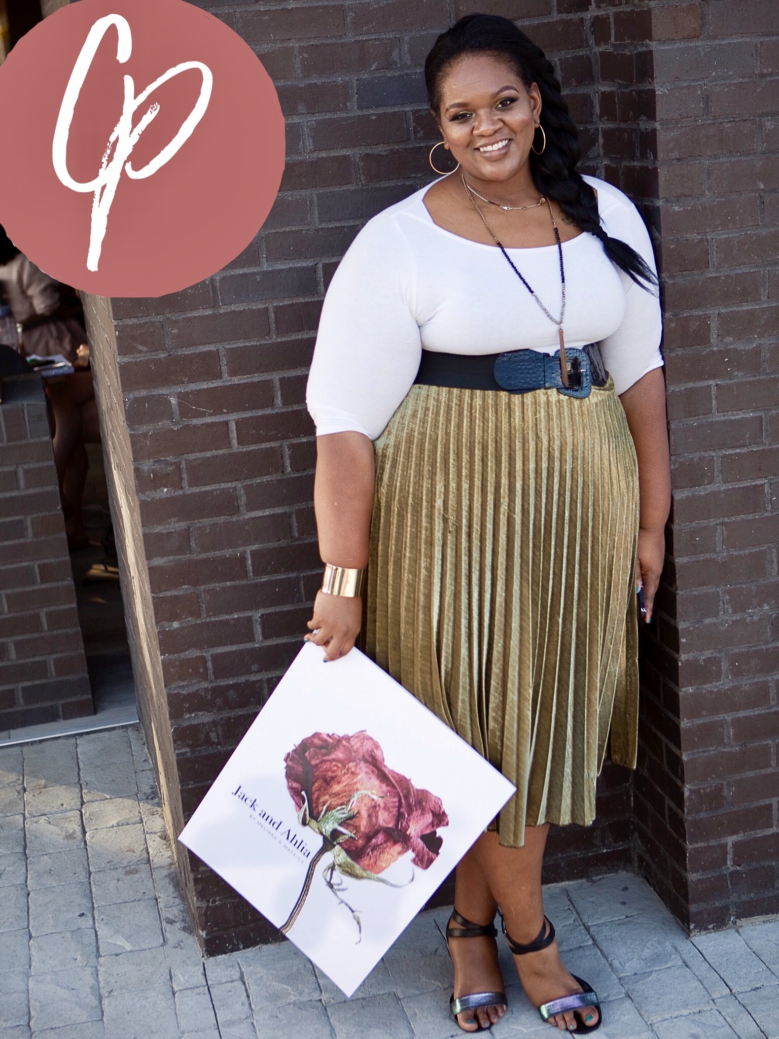 Blogger holding a sign standing next to brick wall